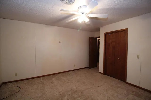an empty room with a ceiling fan and a window