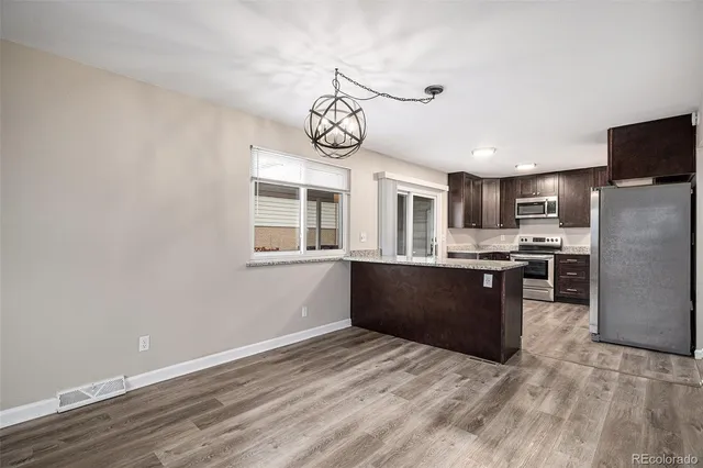 a large kitchen with stainless steel appliances granite countertop a stove a sink dishwasher a refrigerator and wooden floor