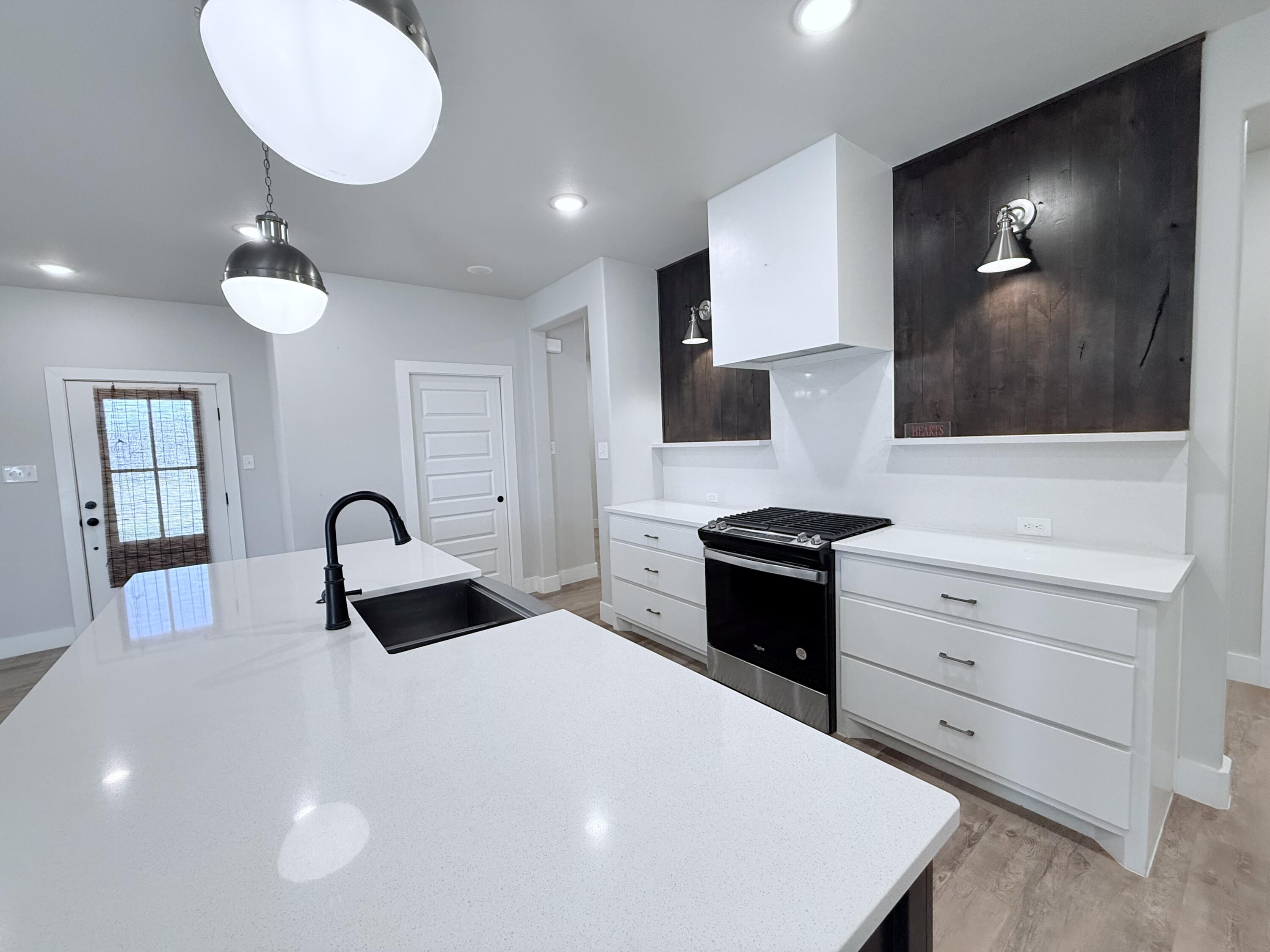 2915 137th Street Lubbock, TX 79423 - Photo 23 of 40 a kitchen with a stove a sink and a flat screen tv