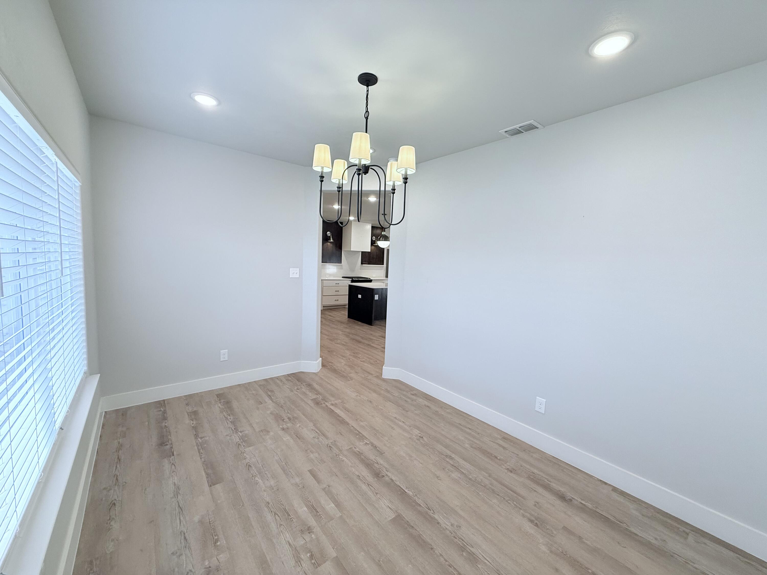 2915 137th Street Lubbock, TX 79423 - Photo 7 of 40 an empty room with wooden floor and chandelier