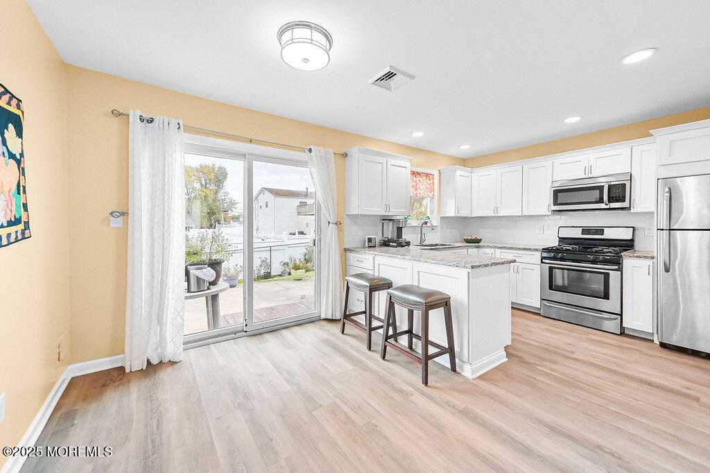 9 Tralee Road Hazlet, NJ 07730 - Photo 13 of 40 a kitchen with a refrigerator a stove top oven a sink dishwasher and white cabinets with wooden floor