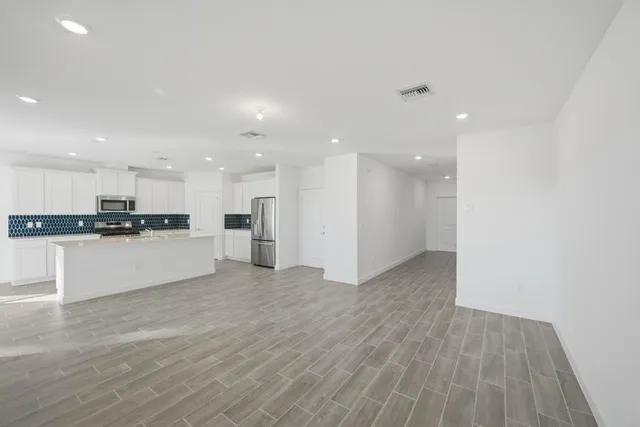 a view of kitchen with kitchen island white cabinets and stainless steel appliances