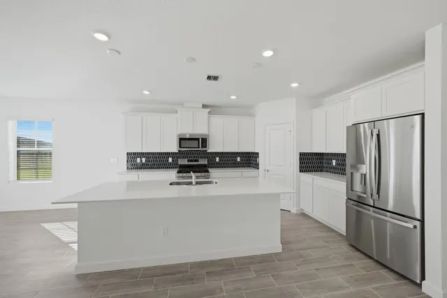 a kitchen with stainless steel appliances a refrigerator sink and white cabinets