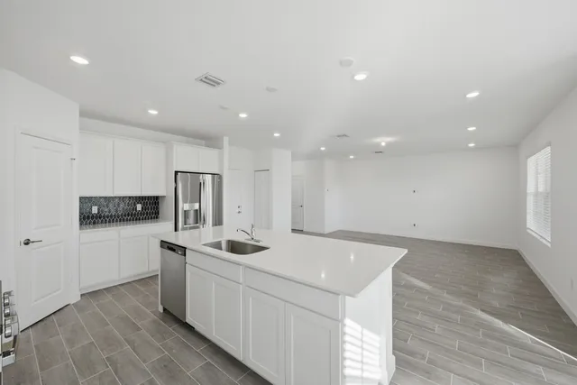 a kitchen with a sink a refrigerator and white cabinets
