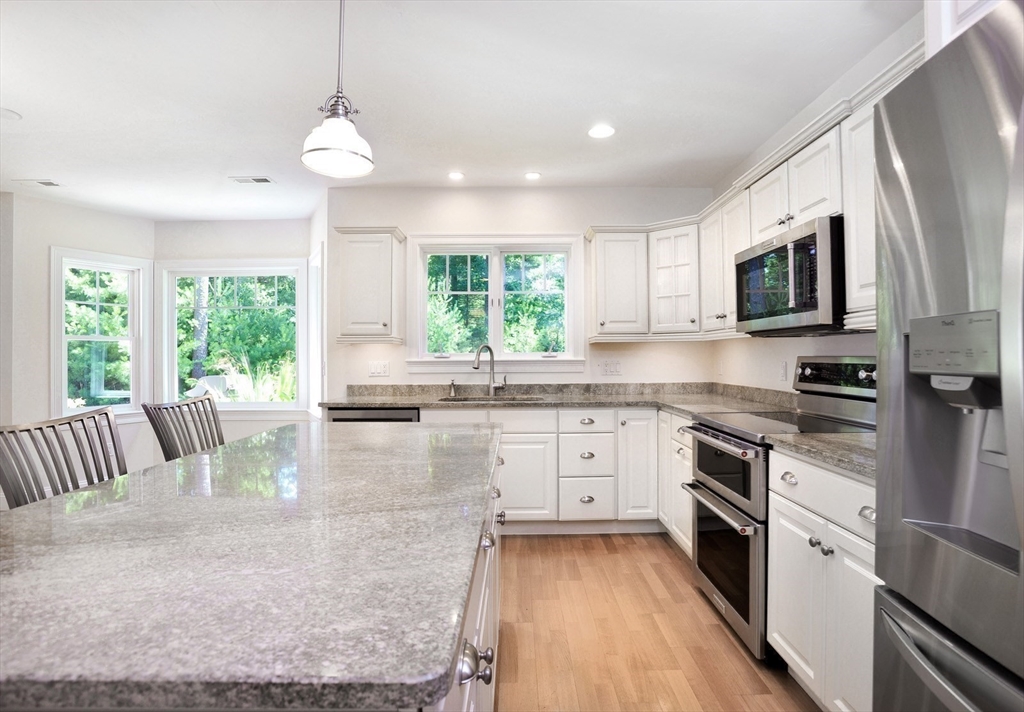 20 Mariner's Drive, Unit 20 Marshfield, MA 02050 - Photo 10 of 26 a kitchen with stainless steel appliances granite countertop a stove top oven a sink dishwasher a dining table and chairs with wooden floor