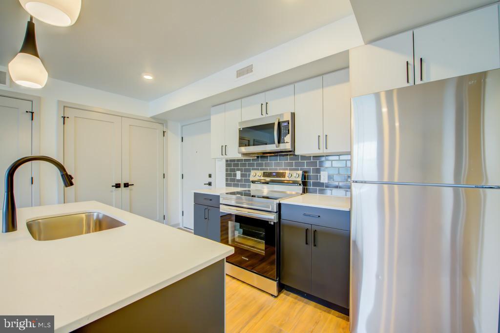 a kitchen with kitchen island a sink stainless steel appliances and refrigerator