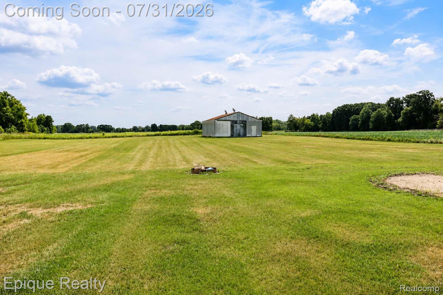 10179 Duffield Road Gaines, MI 48436 - Photo 27 of 30 Expansive green space featuring a metal barn, distant treeline, and a sand area