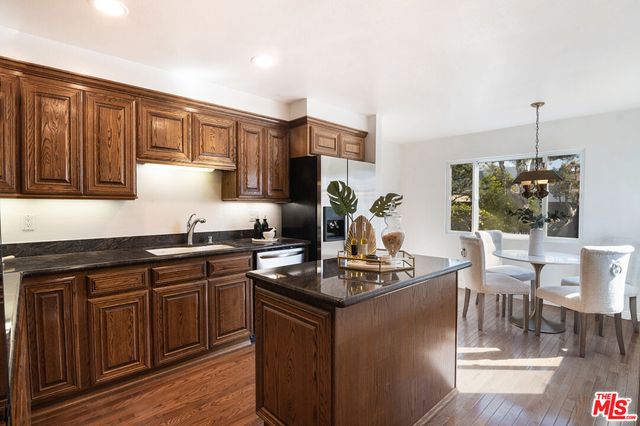 a kitchen with stainless steel appliances granite countertop a stove a sink dishwasher and cabinets with wooden floor