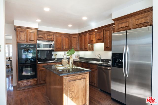 a kitchen with kitchen island granite countertop stainless steel appliances and wooden cabinets