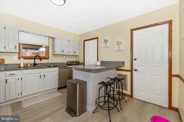 a kitchen with granite countertop white cabinets and chairs