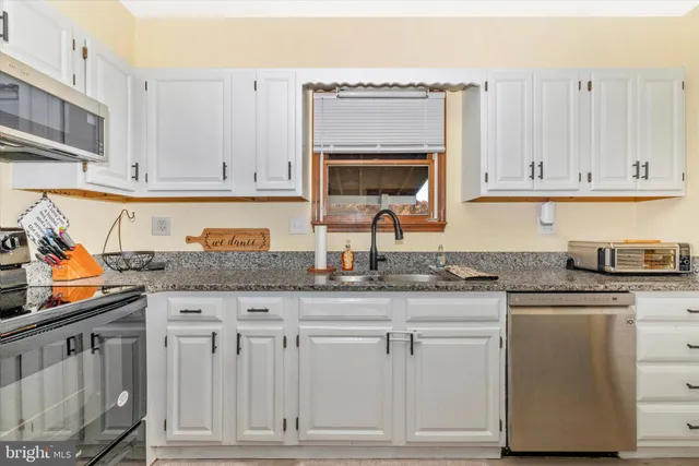 a kitchen with granite countertop white cabinets and a stove