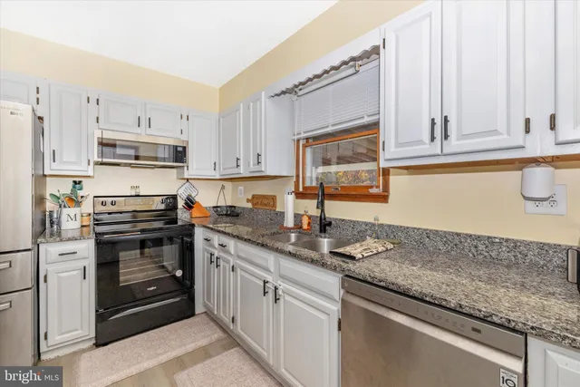 a kitchen with stainless steel appliances granite countertop a sink stove and cabinets