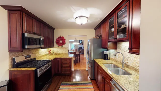 a kitchen with stainless steel appliances granite countertop a stove top oven a sink dishwasher and cabinets with wooden floor