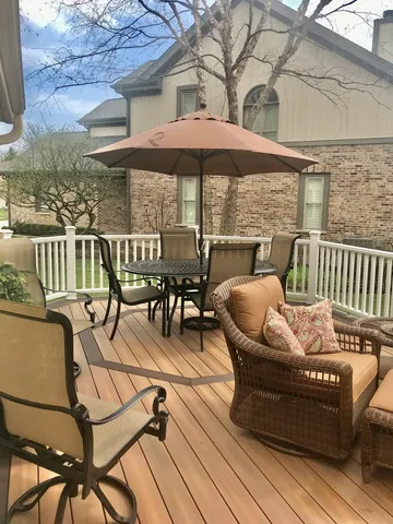 a view of a patio with couches table and chairs under an umbrella