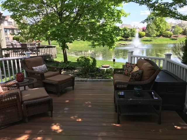a view of a patio with couches chairs and a table and chairs with wooden floor and fence