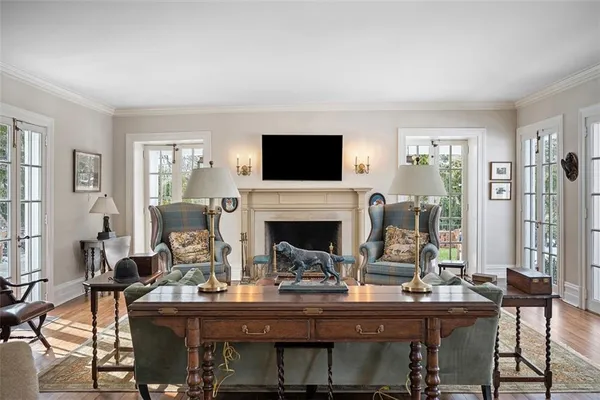 a living room with furniture a rug a chandelier and a book shelf