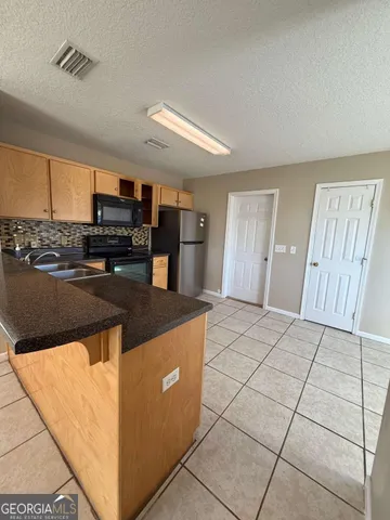 a kitchen with granite countertop a refrigerator and a stove top oven