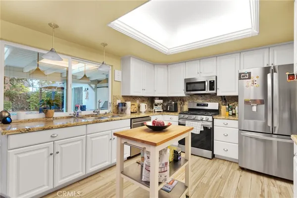 a kitchen with a stove and white cabinets with wooden floor