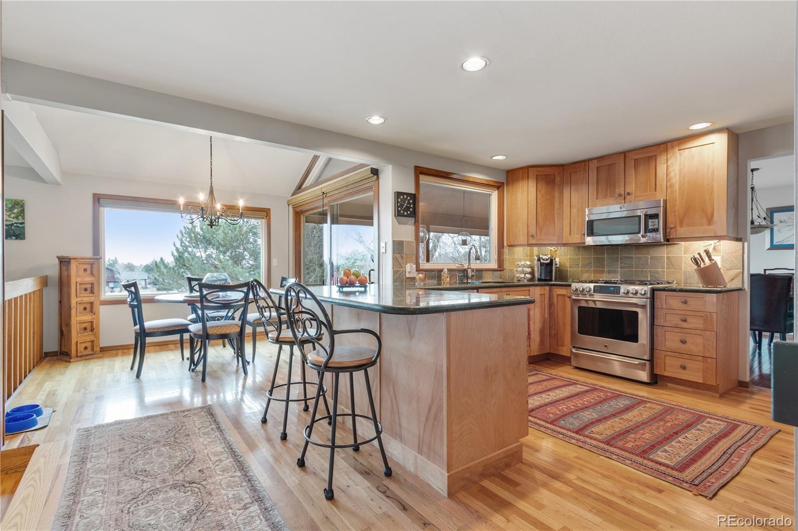 6674 Fairways Drive Longmont, CO 80503 - Photo 11 of 40 a kitchen with stainless steel appliances granite countertop a stove top oven a sink dishwasher a dining table and chairs with wooden floor