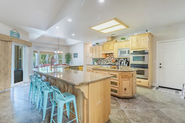 a kitchen with stainless steel appliances kitchen island granite countertop a table chairs in it and white cabinets