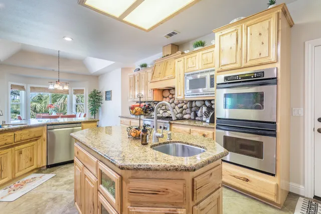 a kitchen with stainless steel appliances granite countertop a sink stove and refrigerator