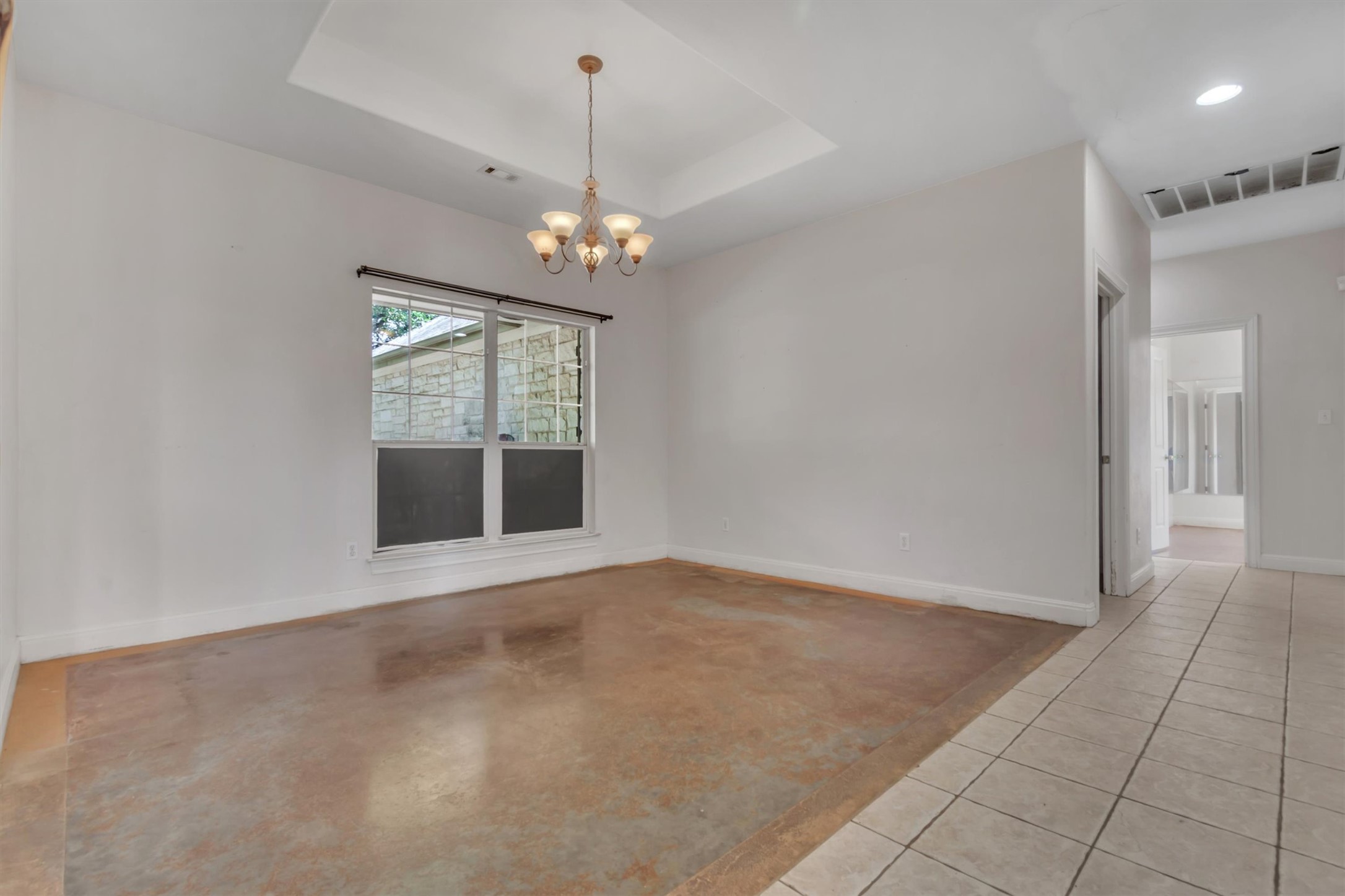 1120 Meadow Ridge Drive Austin, TX 78737 - Photo 7 of 40 A tray ceiling with a chandelier illuminates this adaptable living area with concrete flooring.