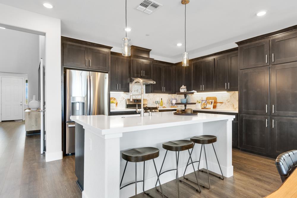 8435 Kyler Road Elk Grove, CA 95757 - Photo 2 of 56 a kitchen with stainless steel appliances a refrigerator a stove a kitchen island with chairs and wooden floor