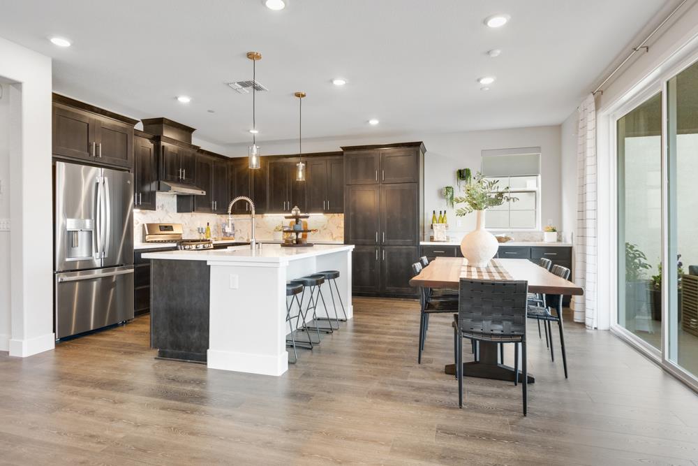 8435 Kyler Road Elk Grove, CA 95757 - Photo 4 of 56 a kitchen with stainless steel appliances kitchen island granite countertop a refrigerator a stove a sink a dining table and chairs with wooden floor