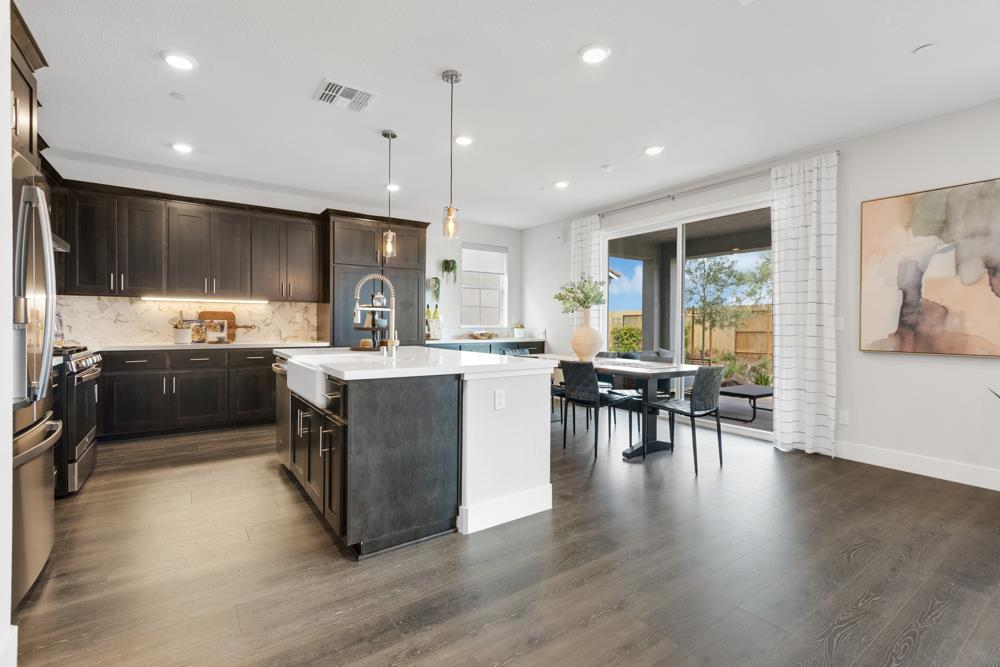 8435 Kyler Road Elk Grove, CA 95757 - Photo 6 of 56 a kitchen with stainless steel appliances granite countertop a stove top oven a sink dishwasher a dining table and chairs with wooden floor