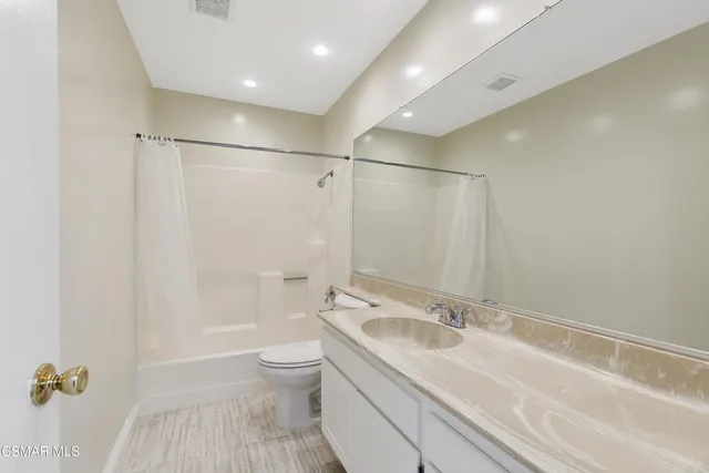 a bathroom with a granite countertop sink a toilet and shower