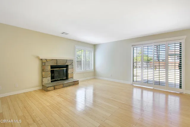 a view of empty room with wooden floor and fireplace