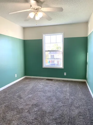 an empty room with a window and a ceiling fan