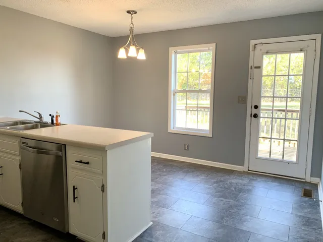 a utility room with stainless steel appliances a stove a sink and a window