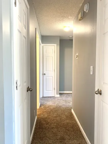 view of a hallway with wooden floor and a bathroom
