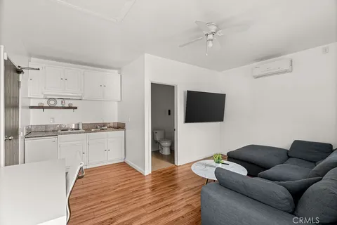 a living room with stainless steel appliances furniture and a flat screen tv