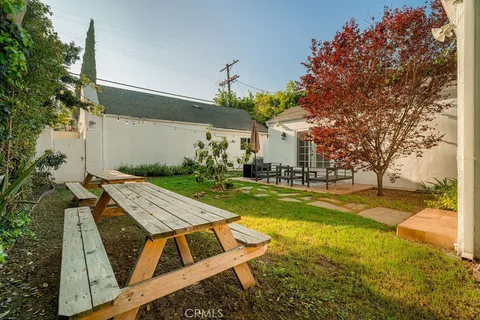 a view of a patio with table and chairs potted plants and large tree