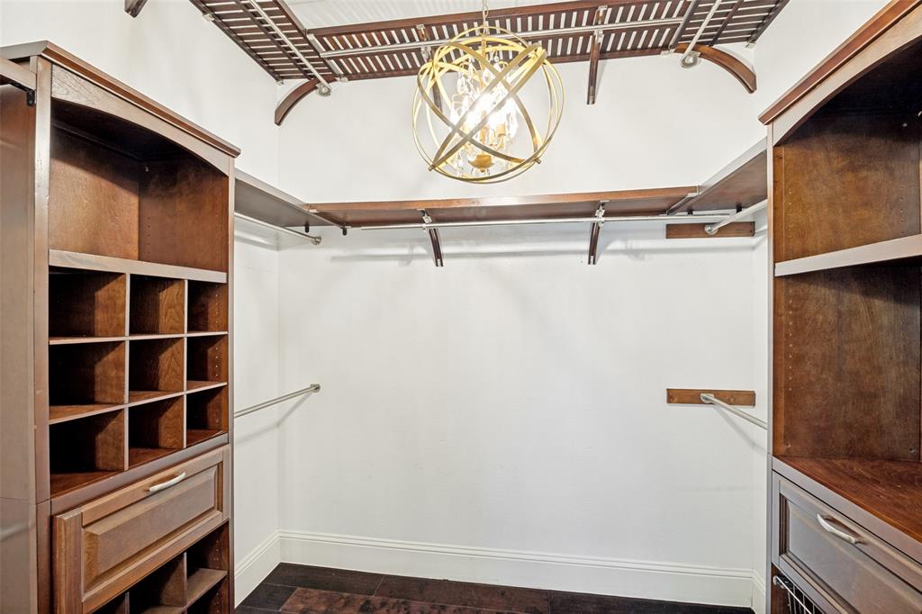 2100 Los Rios Boulevard Plano, TX 75074 - Photo 17 of 25 Custom walk-in closet featuring wood-finish cabinetry, built-in shelving, hanging rods, and a decorative orb chandelier