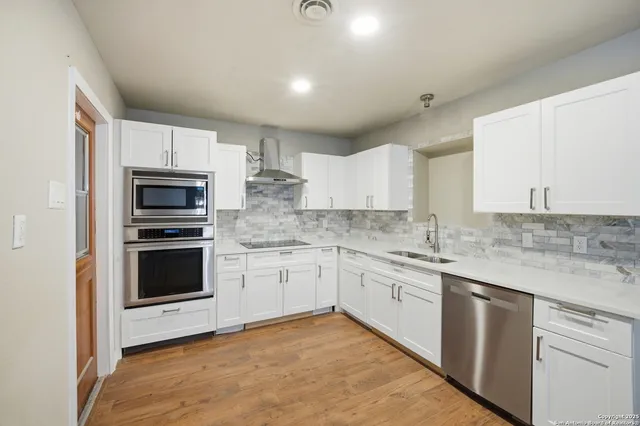 a view of a kitchen with kitchen island a sink dishwasher a stove and a refrigerator with wooden floor