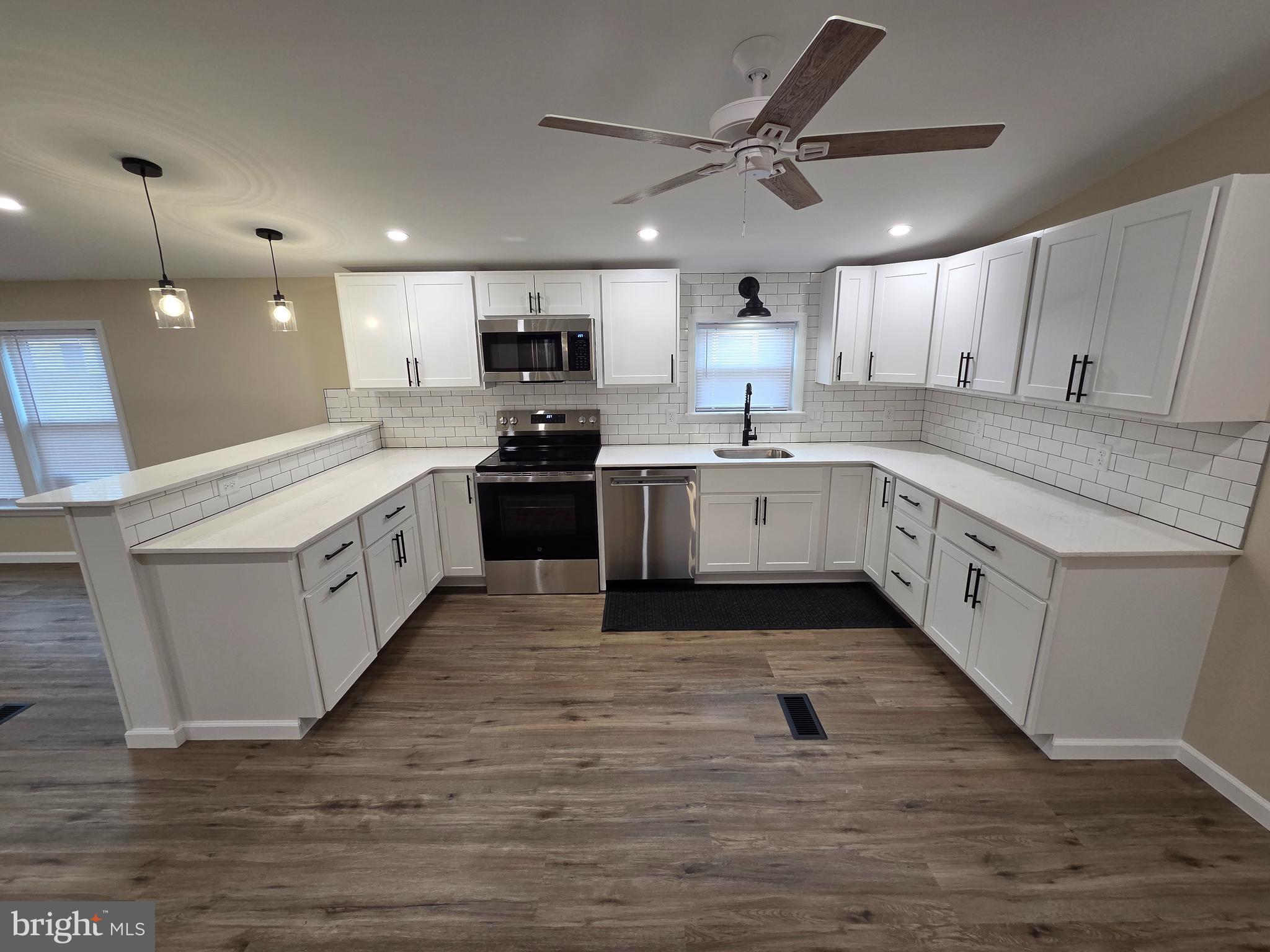a large kitchen with stainless steel appliances granite countertop a stove oven and a white cabinets