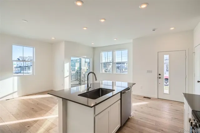 a kitchen that has a sink and a stove with wooden floor