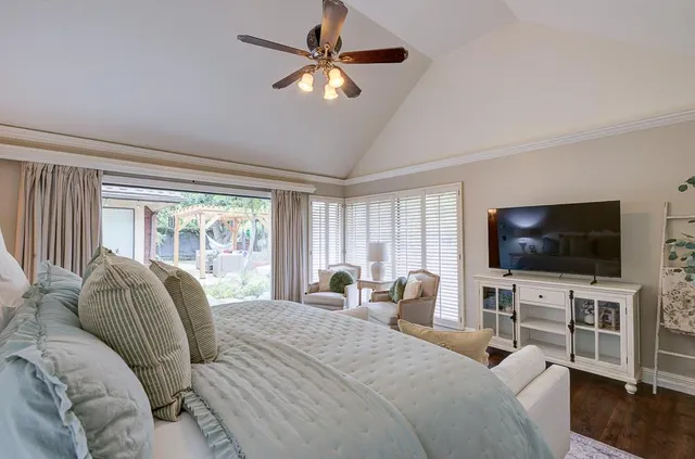a bedroom with bed a flat tv and a large window