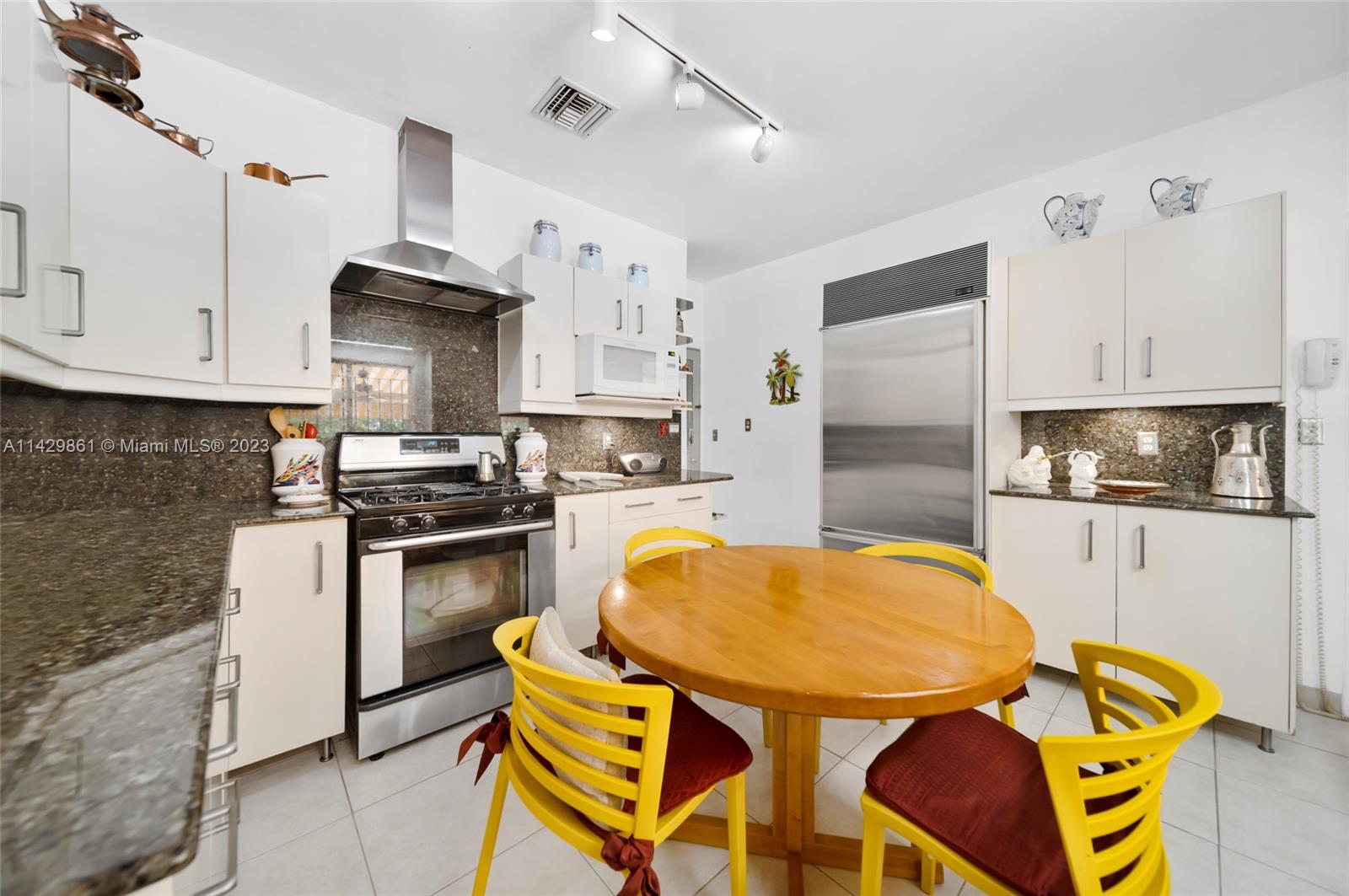 2935 North Bay Road Miami Beach, FL 33140 - Photo 19 of 27 a kitchen with stainless steel appliances kitchen island granite countertop a sink a stove a refrigerator cabinets and chairs