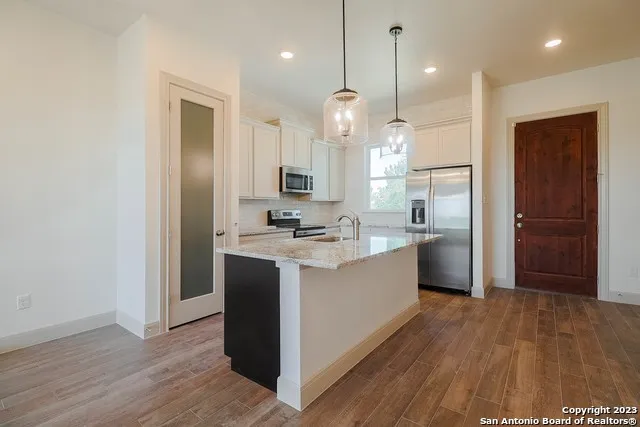 a large kitchen with a lot of counter space and wooden floor
