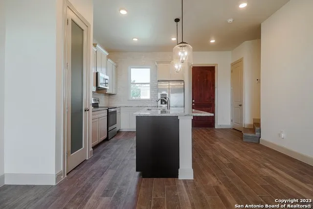 a kitchen with kitchen island wooden floors appliances and cabinets