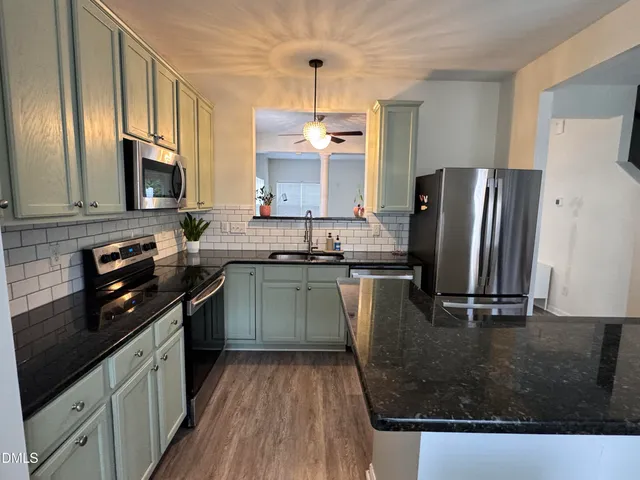 a kitchen with a sink a counter top space cabinets and stainless steel appliances