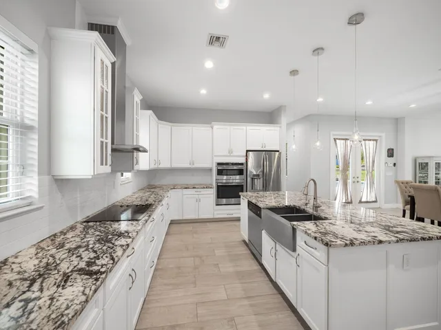 a large kitchen with stainless steel appliances granite countertop a lot of counter space and wooden floor