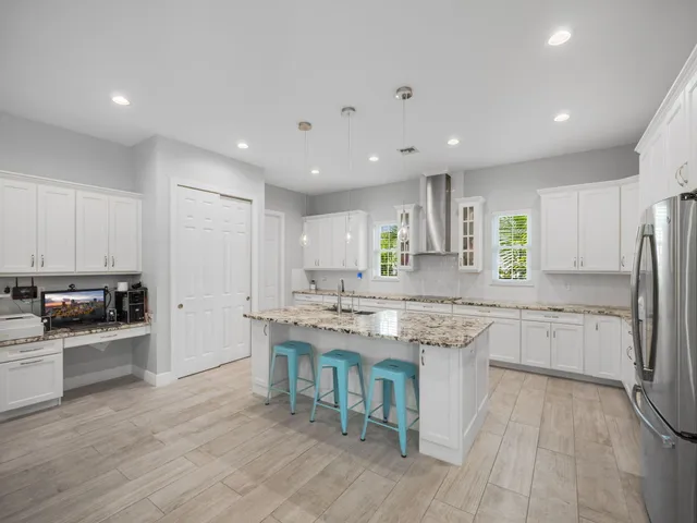 a kitchen with stainless steel appliances granite countertop a stove top oven a sink dishwasher a refrigerator and a dining table with wooden floor