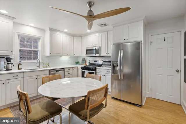 a kitchen with stainless steel appliances granite countertop a refrigerator a sink a stove a dining table and chairs