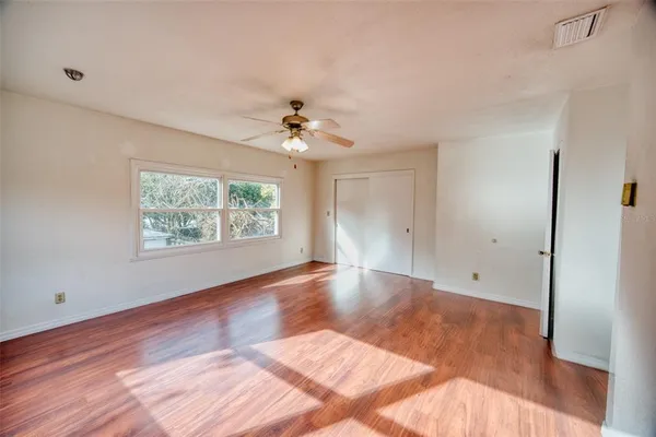 an empty room with wooden floor and windows