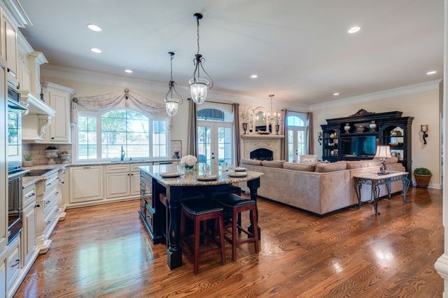 a living room with furniture kitchen view and a wooden floor